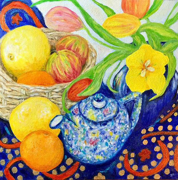 Vibrant still life with a blue speckled china teapot, yellow and pink tulips, a basket of lemons and apples on a rich blue and gold patterned cloth – oil painting by Joan Hudson