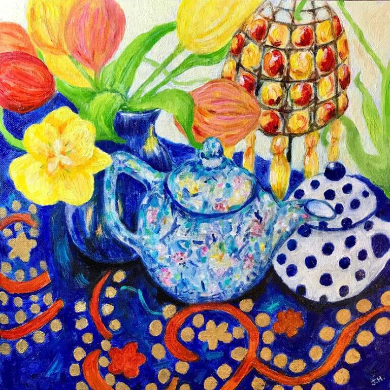Colourful still life with a blue speckled teapot, orange and yellow tulips, a beaded decorative lamp and a polka dot bowl on a rich blue patterned cloth – oil painting by Joan Hudson